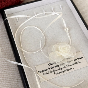 Detail of organza rose necklace with pearl center in a black wood jewelry box