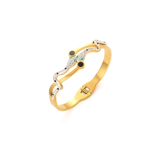 Macro shot of gold snake bracelet head featuring sparkling crystals and green gem eyes