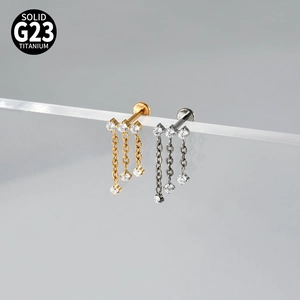Detail of G23 titanium labret studs with zircon clusters and hanging chain tassels