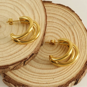 Detailed macro shot of 18K gold plated multi-layer hoop earrings on a rustic wood surface