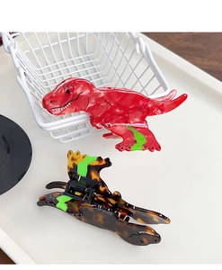 Detail of red and tortoiseshell dinosaur hair claws on a minimalist white tray