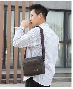 Dark brown leather shoulder bag detail with multiple zipper compartments and adjustable strap