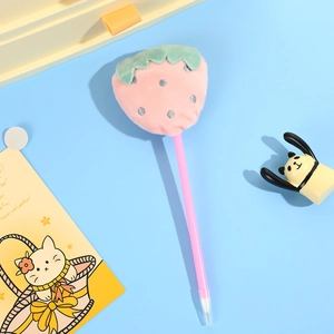 Close-up of pink plush strawberry ballpoint pen with silver dots on blue background