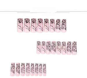 Detail view of pink press-on nails with leopard spots, zebra stripes, and gold star charms