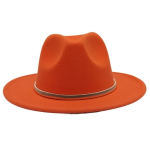 Macro shot of bright orange wool fedora hat with elegant gold metal band decoration