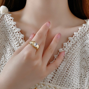 Detailansicht eines goldfarbenen Rings mit quadratischem Zirkon an der Hand