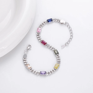 Dettaglio del bracciale in argento con gemme multicolori taglio smeraldo su sfondo bianco