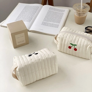 Detailed close-up of quilted cotton makeup bag with red cherry embroidery and zipper