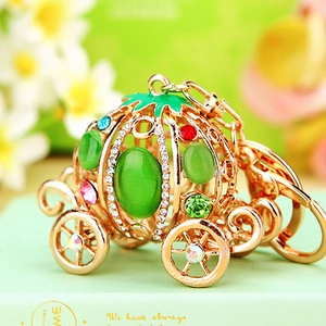 Golden carriage keychain with colorful rhinestones and green gems on floral background