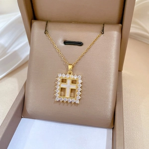 Close-up of golden cross necklace with crystal pavé pendant in a brown jewelry box