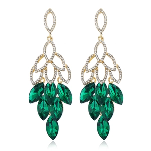 Détail de boucles d'oreilles dorées avec cristaux marquise verts et strass blancs