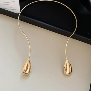 Detailed close-up of golden teardrop pendant on minimalist metal choker necklace