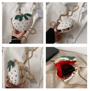 Macro shot of strawberry shaped mini bag with gold studs and red fabric lining interior
