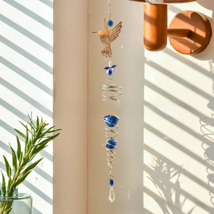 Detail of golden hummingbird wind chime with blue crystal beads and spiral metal frame