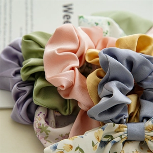 Detailed view of floral and solid satin scrunchies with double layer bow designs