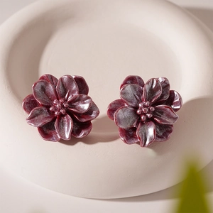 Détail de boucles d'oreilles fleurs en résine rouge rétro avec bords givrés blancs