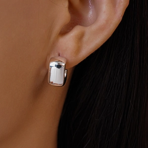 Detailed close-up of polished silver huggie earrings with a wide rounded rectangular design