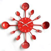 Close-up of red kitchen clock featuring cutlery hands and radial utensil design