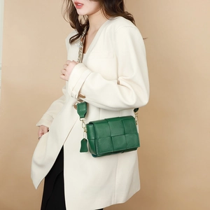 Detail of green woven leather texture on a high-quality crossbody bag with wide strap