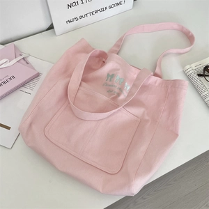Detailed view of pink canvas tote bag featuring delicate blue bow embroidery and side pockets