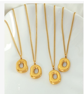 Detailed view of four gold D-shaped pendant necklaces on a white ceramic plate
