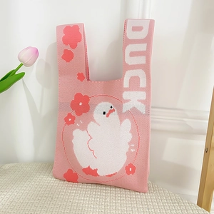 Close-up of pink knitted tote bag featuring a white cartoon duck and floral pattern