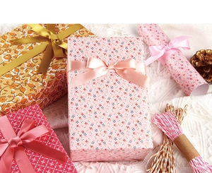 Gros plan sur du papier cadeau floral avec rubans de satin et ficelle de coton décorative
