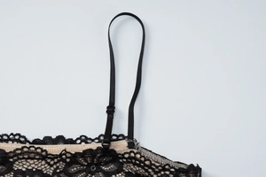 Detail view of the adjustable thin shoulder strap with black metal buckle on lace dress