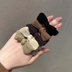 Close-up of bow knot elastic hair ties in neutral colors shown on hand model