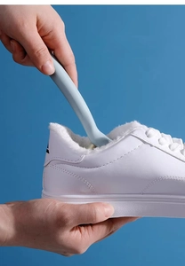 Detail of soft-bristled cleaning brush being used on the heel of a white sneaker