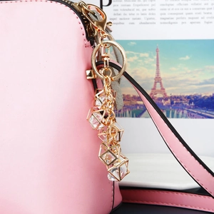 Close-up of pink leather bag charm with five gold geometric crystal cube pendants