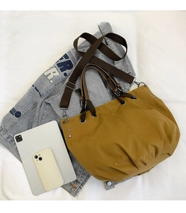 Detailed view of yellow vintage tote bag size comparison with an iPad and phone
