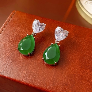 Vue macro de boucles d'oreilles vintage avec zircon coeur et pierre verte en goutte