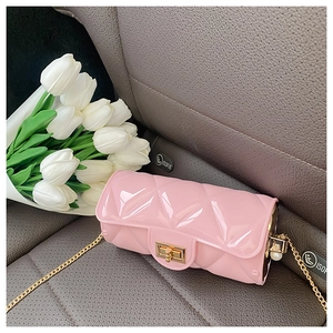Pink quilted cylinder bag with gold chain and pearl detail on a grey car seat