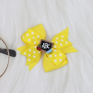 Detail of yellow polka dot ribbon bow hair clip with ABC blackboard and pencil ornament