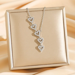 Luxurious silver heart necklace with five sparkling crystal pendants on silk background