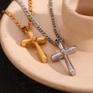 Detail view of gold and silver cross pendants on a classic Figaro chain necklace