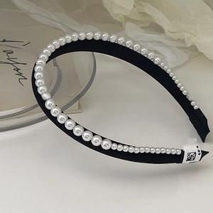 Detail of elegant satin double-layer headband with symmetrical white pearls and black fabric