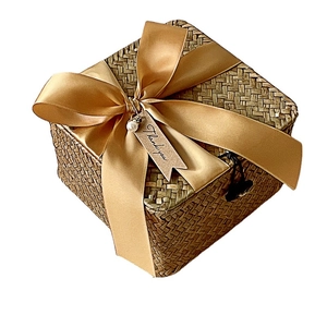 Square woven rattan gift basket with gold ribbon bow and Thank You tag on white background