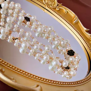 Baroque multi-layer pearl necklace with camellia charms on a vintage gold mirror