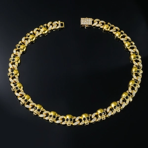 Macro shot of gold punk skull necklace links with black gemstone eyes and crystals