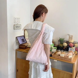 Detailed texture of pink and white checkered canvas tote bag worn by a person