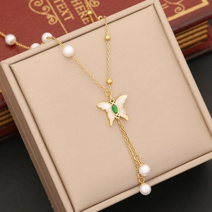 Detail of gold butterfly pendant with green gemstone and pearl charms on jewelry box