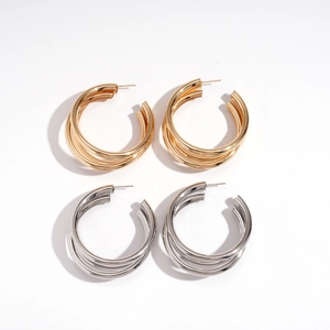 Triple layer geometric C-shape earrings in gold and silver finishes on white background
