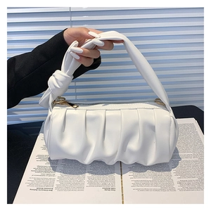 Detail of white pleated cloud bag with soft knotted handle and elegant gold zipper
