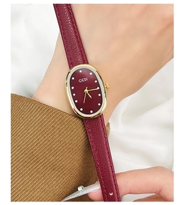Gros plan d'une montre à quartz vintage avec bracelet en cuir rouge sur un poignet