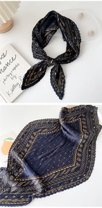 Detail of pleated navy blue silk scarf with golden vintage pattern on white desk
