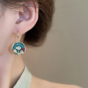 Close-up of vintage gold-plated drop earrings with blue enamel flower and pearl details