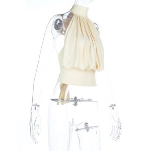 Detail eines beigen Neckholder-Tops mit Falten-Design und tailliertem Schnitt auf weißem Grund