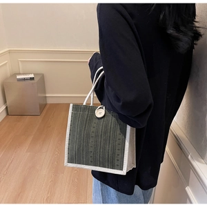 Detail of green striped linen tote bag with cream handles and white decorative button
